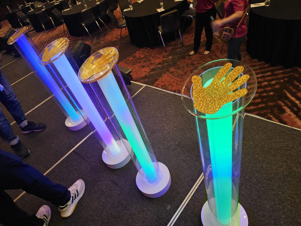 Image features 4 cylinders of Launch Props during a Launch Event. The gimmick is to place the hands on the top of the cylinders to activate the launch.